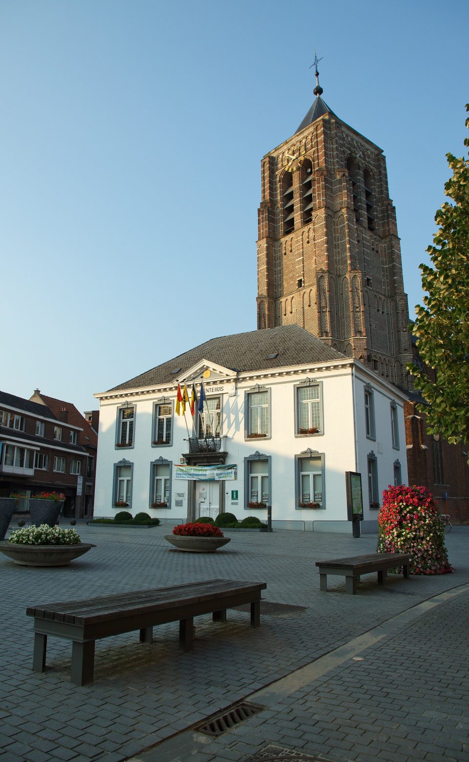 L’ancienne maison communale blanche sur la place du Marché de Mol, avec derrière elle la tour en brique de l’église Saints-Pierre-et-Paul